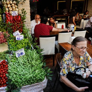 Ein Restaurant mit Menschen neben einem Gemüsestand in Istanbul (Archiv).